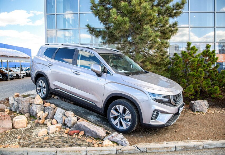 Новый автомобиль Geely Okavango серого цвета у автосалона официального дилера