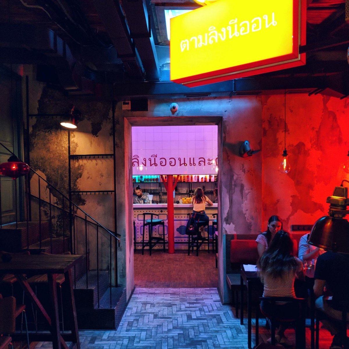 Посетители бара за столиками в неоновом свечении