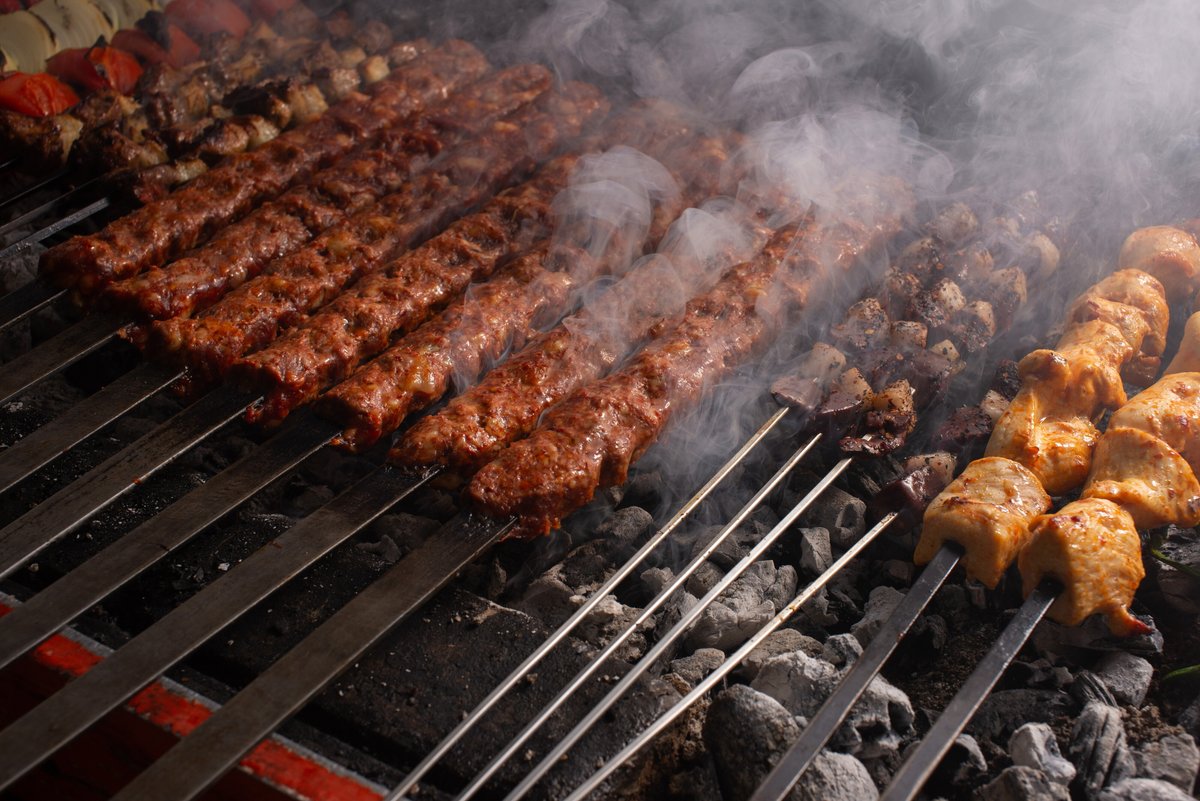 На мангале лежат шампуры с различными видами мяса