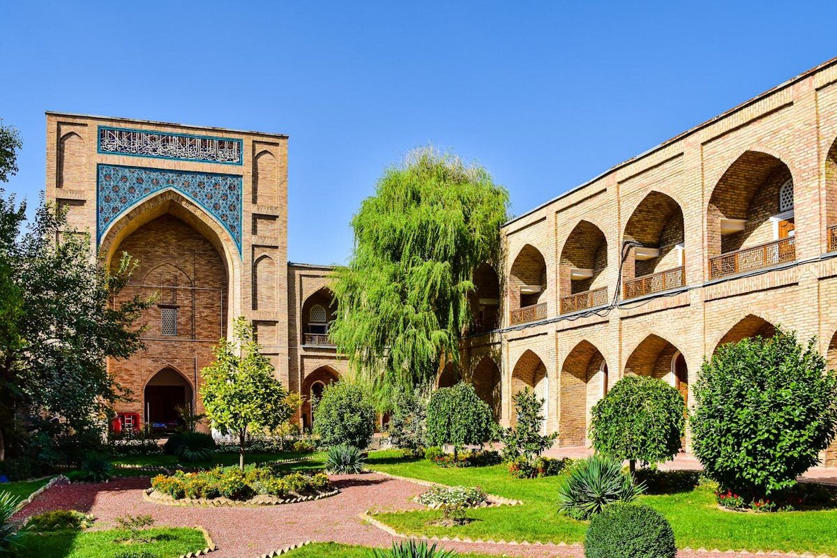 Медресе Кукельдаш летним днём в окружении зелёных деревьев