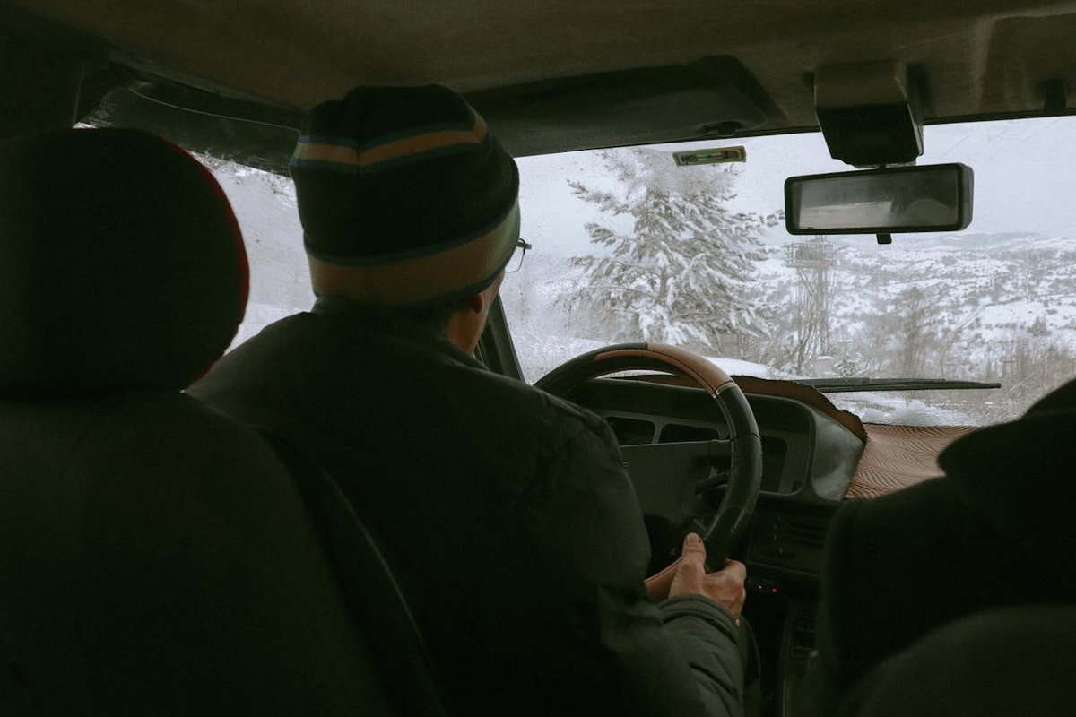Мужчина едет в автомобиле по заснеженной дороге