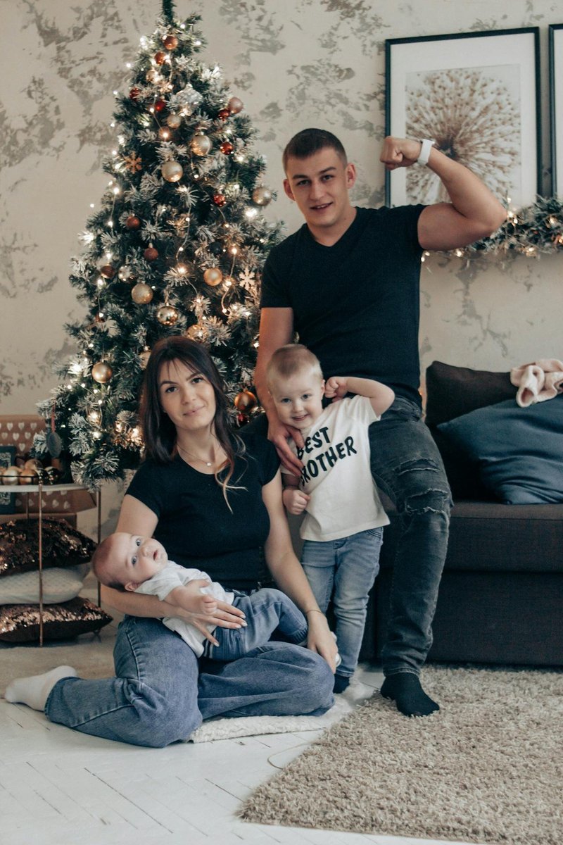 Родители и два маленьких ребёнка около новогодней ёлки