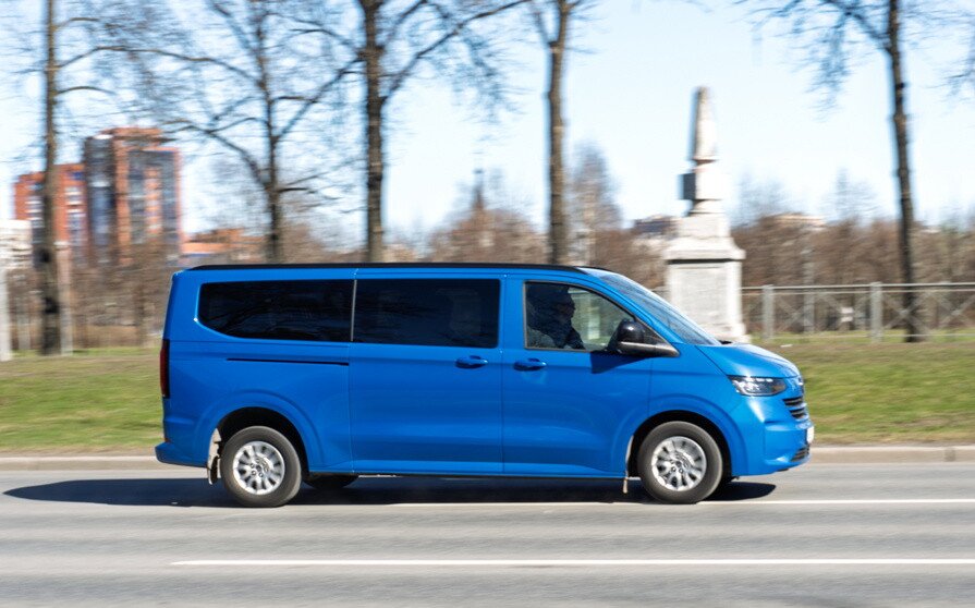 Быстро движущийся синий фургон Volkswagen Multivan T7 на городской дороге