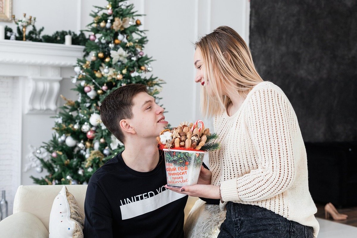 Девушка передаёт новогодний подарок мужчине